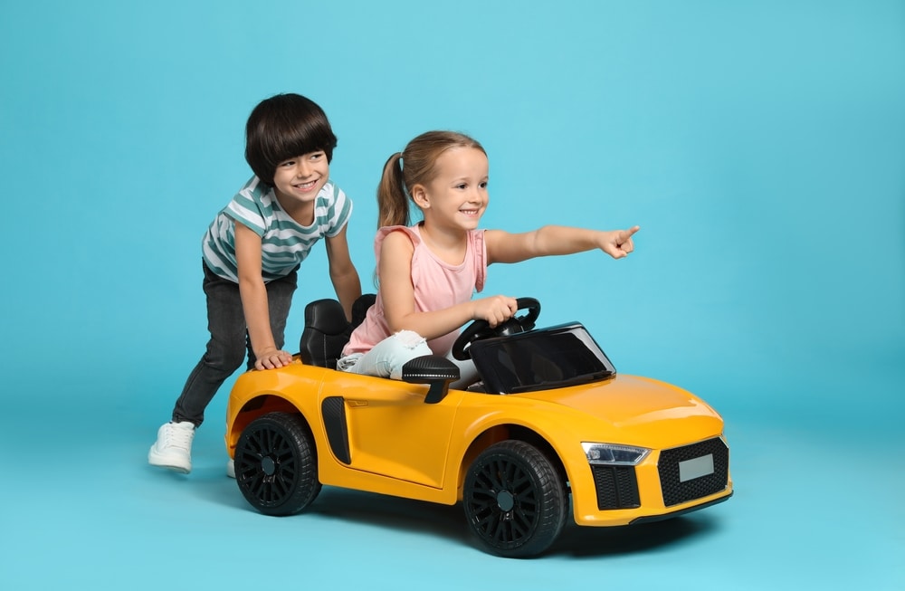 Cute,Boy,Pushing,Children's,Electric,Toy,Car,With,Little,Girl